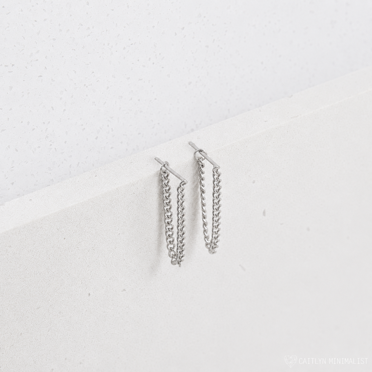 Pair of silver chain earrings on a light gray background